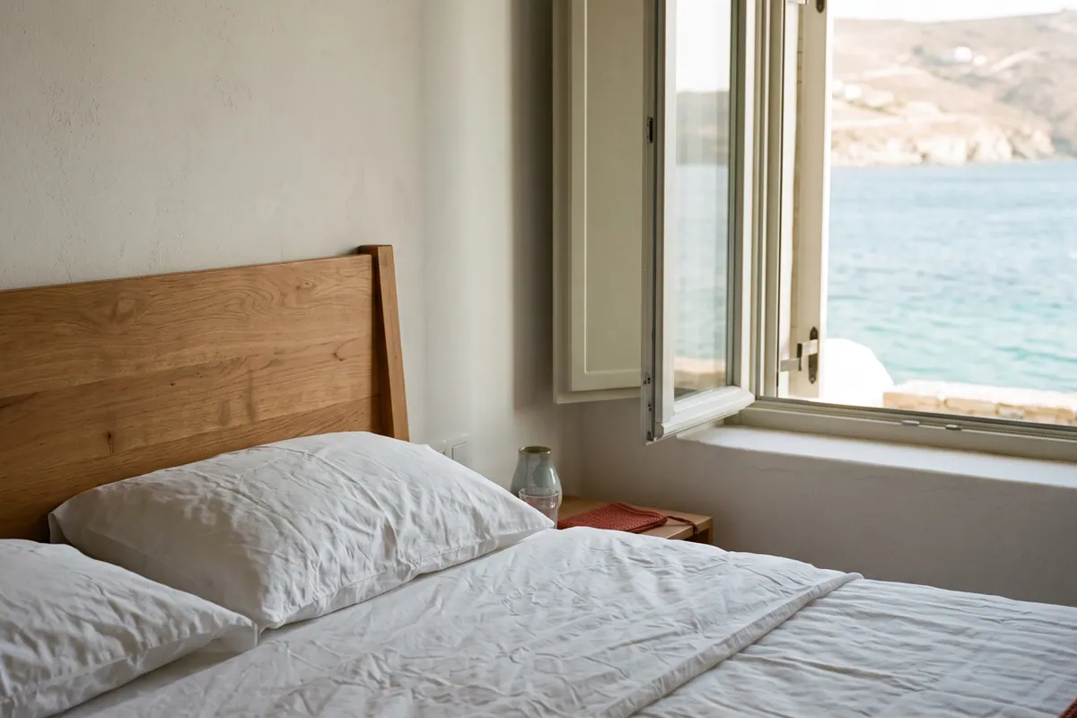 Beyaz keten yatak takımı ve deniz manzaralı pencere olan otel odası
